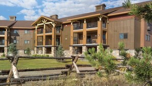 A multi-story hotel with balconies, a stone facade, and a log fence. - Cozy 1-bedroom condo in soothing West Yellowstone with AC (West Yellowstone)
