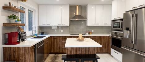 A modern kitchen with white cabinets, stainless steel appliances, and a central island.