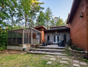 A house with a covered patio, stone steps, and a wooden deck. - Branch & Balsam House
Modern Forest Retreat (Huntsville)