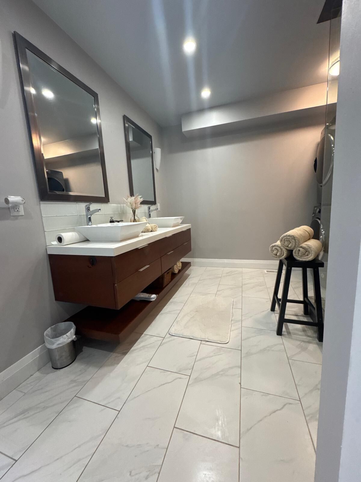 A modern bathroom with two sinks, a mirror, and a towel rack.