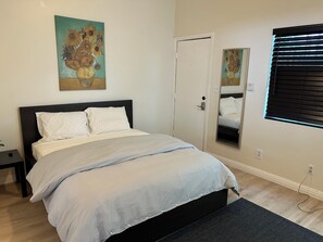 A bedroom with a bed, a bedside table, a mirror, and artwork on the wall. - F, Comfy Studio in Vibrant DTLA (Los Angeles)