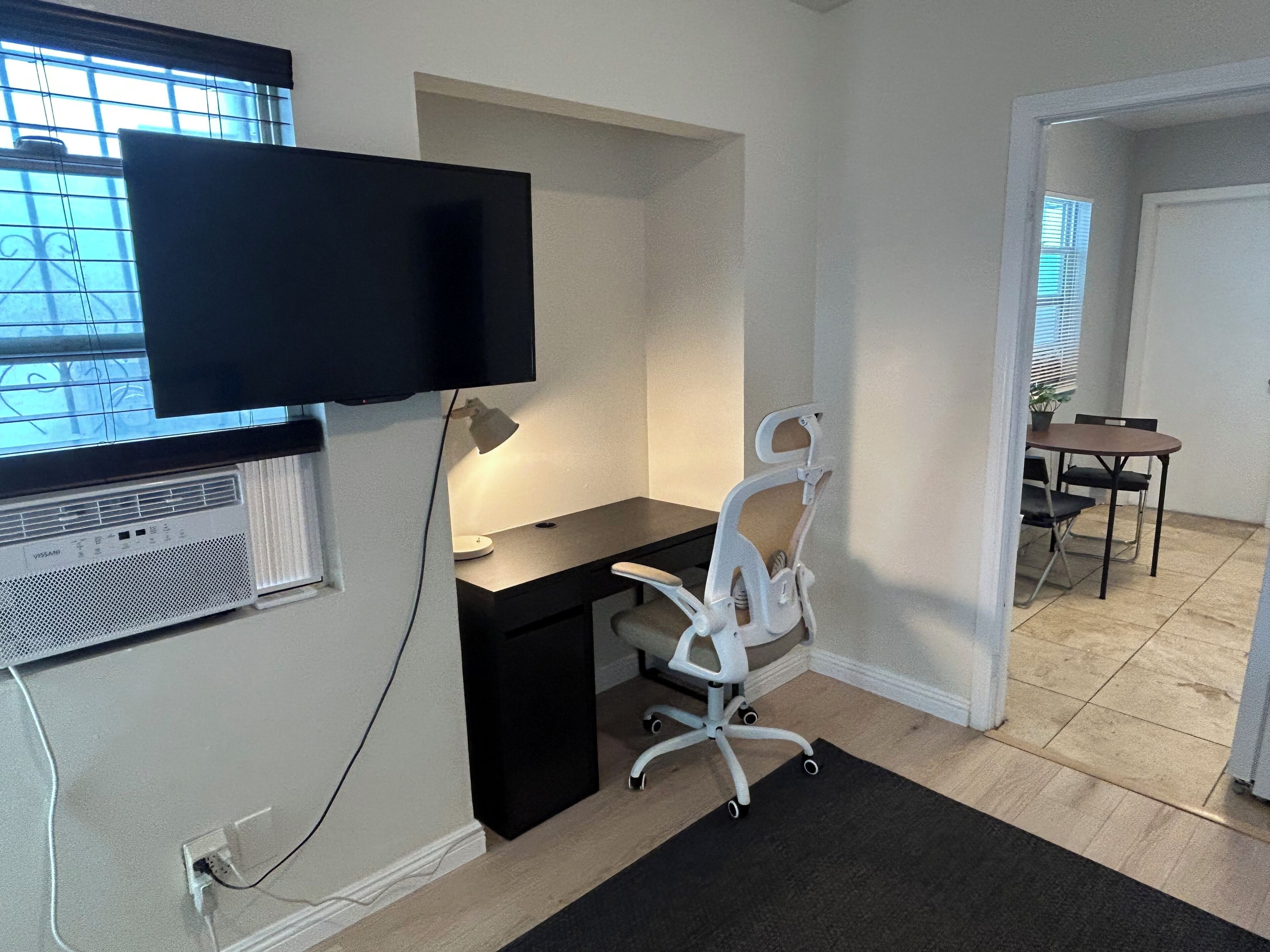 Un espace de bureau moderne comprenant un bureau, une chaise et un téléviseur à écran plat fixé au mur.