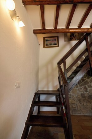 Eine Holzt Treppe mit einer Steinsäule und einem Bild an der Wand.