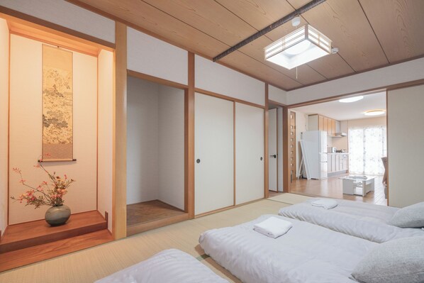A traditional Japanese-style room with tatami flooring, a shoji screen door, and a bed with white bedding. - CEREZO HOUSE
Family/Baby-Friendly 4 bedrooms,2 toilets, 2 bathrooms,Free parking (大阪市西成区天下茶屋3-16-6)