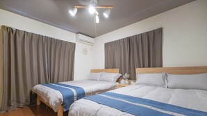 Ett hotellrum med två sängar, en sänggavel i trä, ett nattduksbord med en vas och en takfläkt.