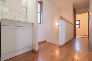 Un pasillo con piso de madera, un gabinete blanco y una ventana.