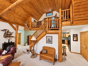 A spacious living area with a wooden staircase leading to an upper level, a fireplace, and a dining area. - Manny's Lakeside Lodge (Mercer)