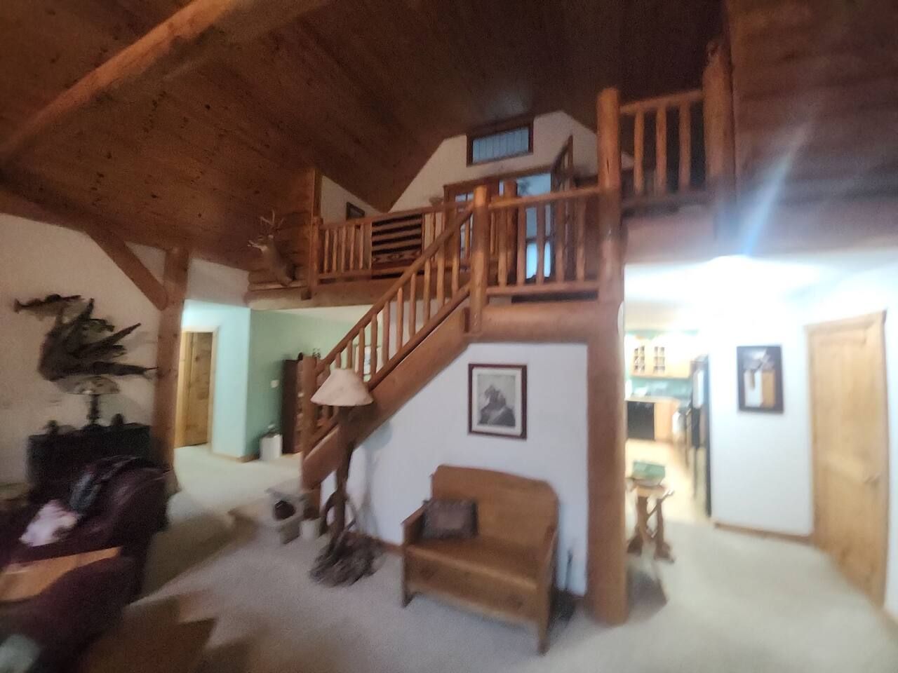 Ein geräumiger Wohnbereich mit einer Holztreppe, einem Sofa, einer Lampe und einem gerahmten Bild an der Wand.