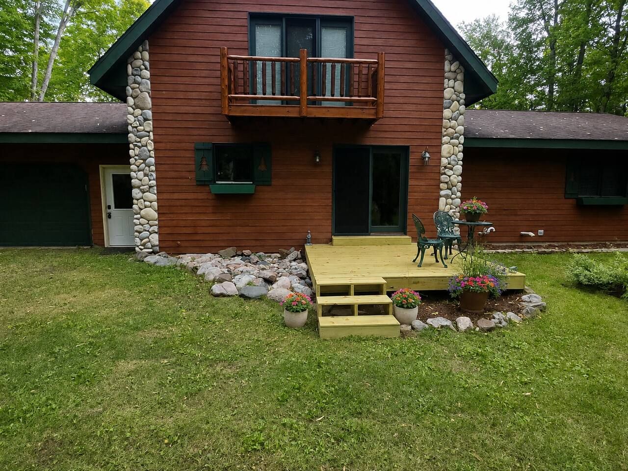 Une cabane en bois dotée d’un balcon, d’une porte d’entrée et d’un petit porche avec des marches menant à une table et à des chaises.