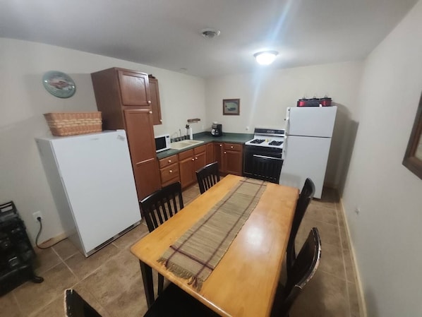 Une cuisine compacte comprenant une table à manger, des chaises, un réfrigérateur et un four à micro-ondes.
