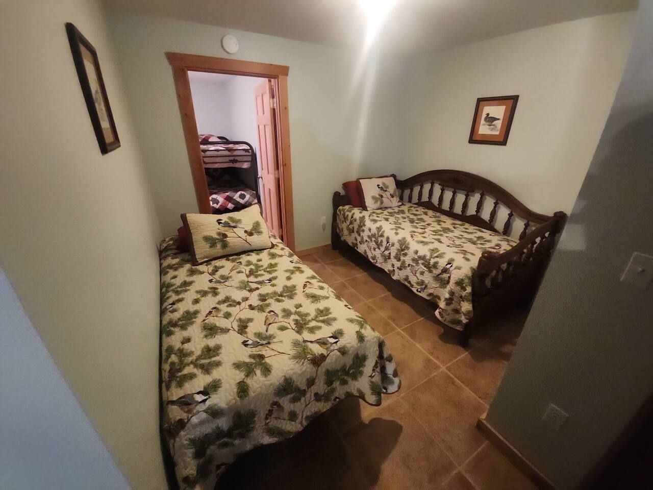 Ein Schlafzimmer mit zwei Betten, einem Holzkopfstück, einer Tür zu einem anderen Raum und einem gerahmten Bild an der Wand.