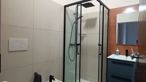 Ein modernes Badezimmer mit einer Duschkabine, einem Bidet, einer Toilette und einem Waschbecken mit Spiegel.