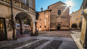 Ein Innenhof mit Kopfsteinpflaster, ein historisches Gebäude mit Backsteinfassade und ein Bogen, der zu einem Gebäude mit Balkon führt.