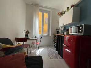 A compact living space with a kitchenette, a dining area, and a window with curtains. - Apartment in Pomposa, in the heart of the city (Modena)