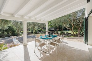 An outdoor patio with a table set for dining, surrounded by chairs, under a white pergola. - Premium Pollensa Country Villa for 6 (Pollença)