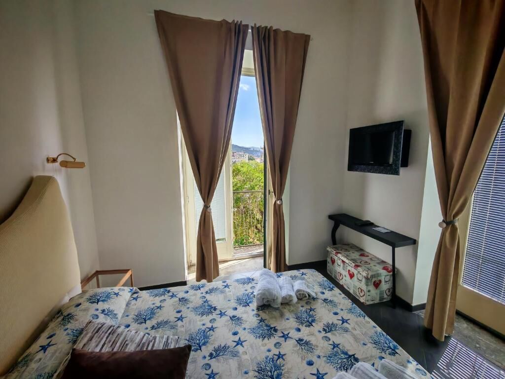 Habitació d'hotel amb un llit, cortines, un televisor i una finestra amb vista.