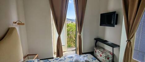 A hotel room with a bed, curtains, a television, and a window with a view.