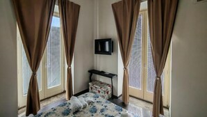 Una habitación de hotel con una cama, cortinas, un televisor y una mesita.