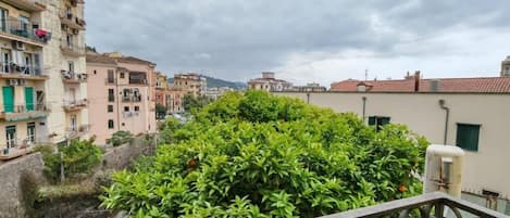 A balcony with a metal railing overlooking a cityscape with buildings and greenery.