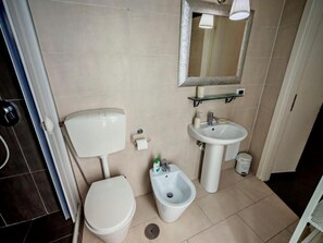 A bathroom with a toilet, bidet, and sink. - A lane of dreams—nature, art, the sea, and the city—nothing could be more complete (Salerno)