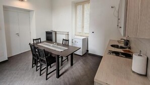 Una cocina compacta con una mesa y sillas, horno integrado y ventana con persianas.