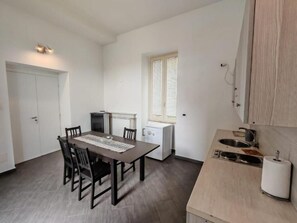 A compact kitchen with a dining table and chairs, a built-in oven, and a window with blinds. - A lane of dreams—nature, art, the sea, and the city—nothing could be more complete (Salerno)