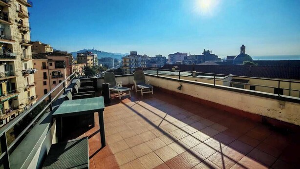 Una terraza en la azotea con vistas al horizonte de la ciudad, una mesa y dos sillas.