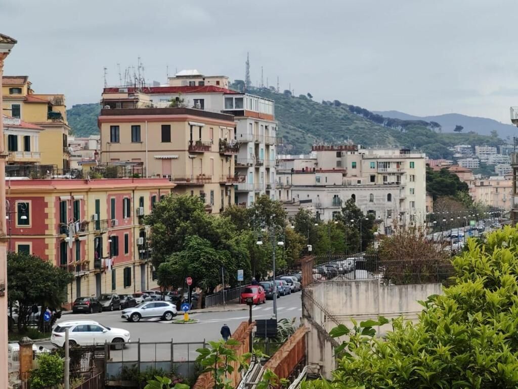 Eine Stadtansicht mit Gebäuden, einer Straße und einer hügeligen Landschaft im Hintergrund.