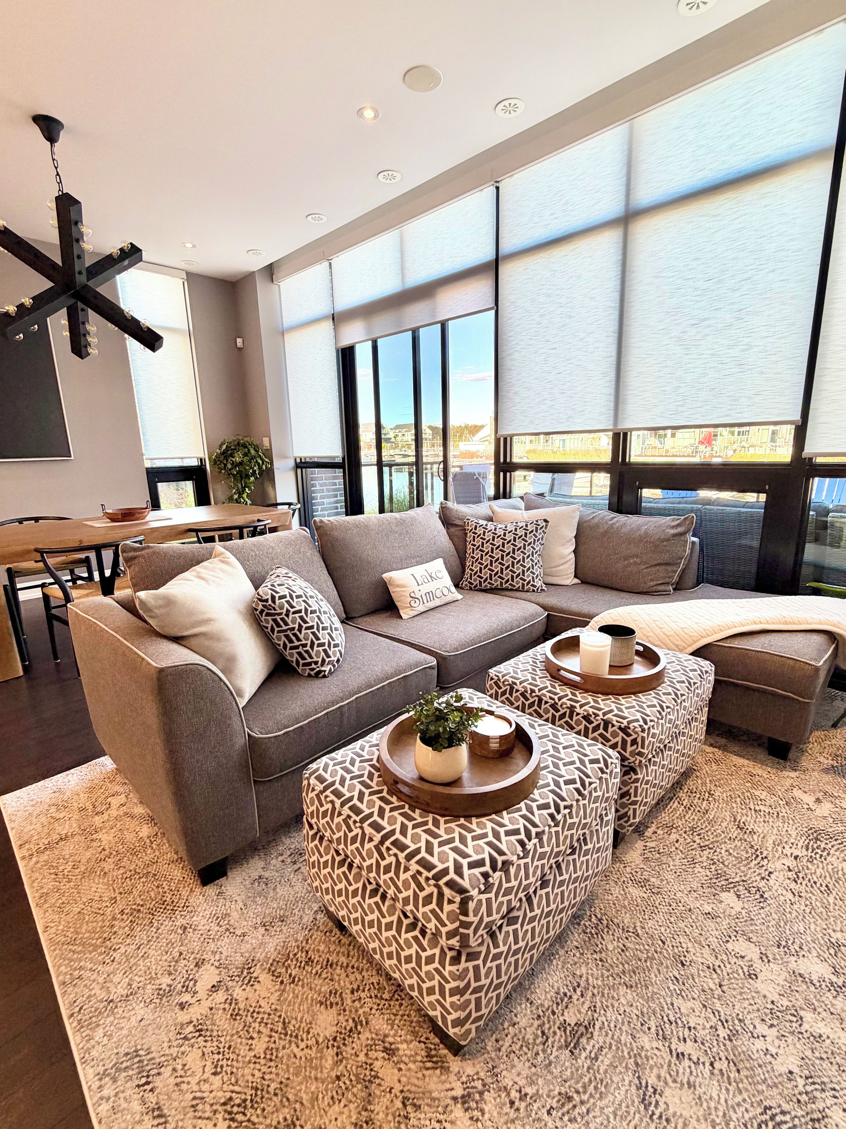 A modern living room with a sectional sofa, ottomans, and a dining area.