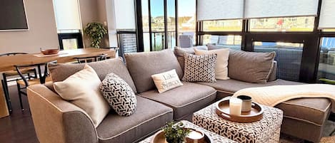 A modern living room with a sectional sofa, ottomans, and a dining area.