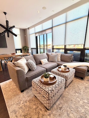 A modern living room with a sectional sofa, ottomans, and a dining area. - Your Friday Harbour Escape Awaits! (Innisfil)