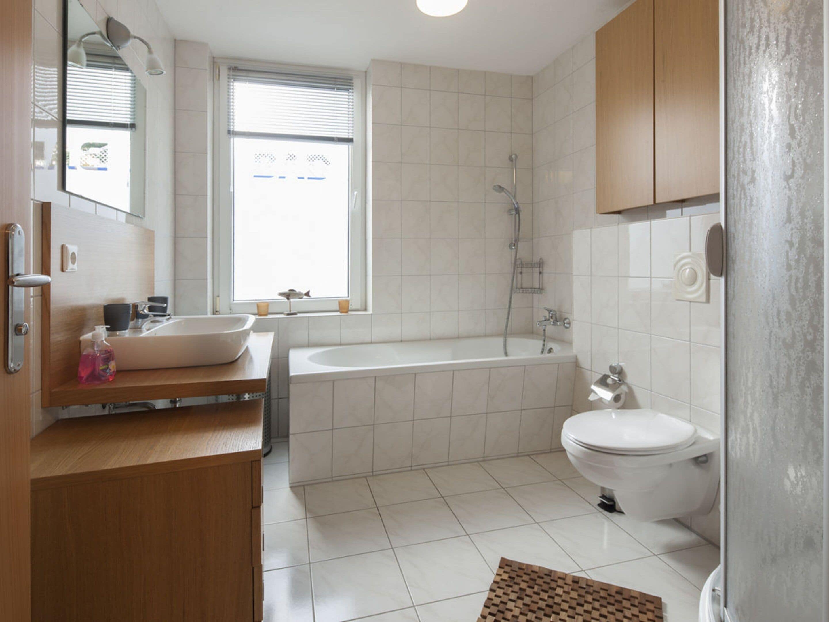 A modern bathroom with a sink, bathtub, and toilet.