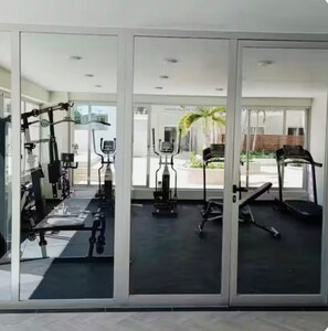 Ein Fitnessraum mit verschiedenen Trainingsgeräten, darunter Laufbändern und Ergometer, und großen Fenstern mit Blick ins Freie.