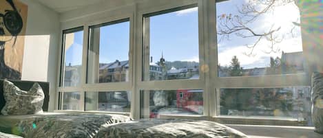 Una habitación con dos camas, ventanas amplias y vistas a un pueblo.