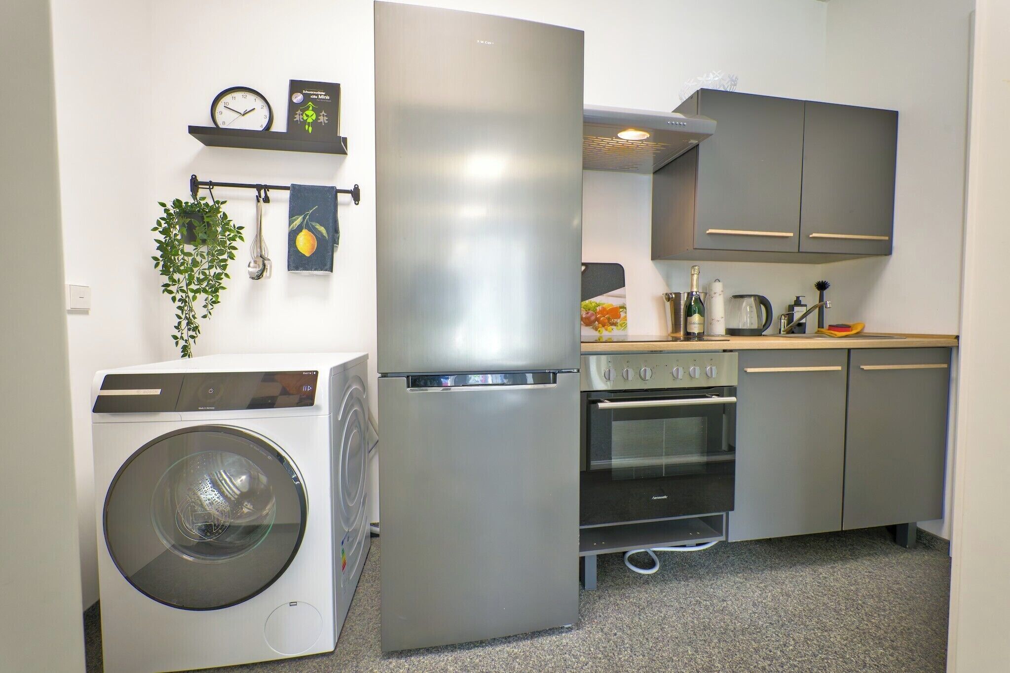 Eine kompakte Küche mit Waschmaschine, Kühlschrank, Backofen und Spüle.