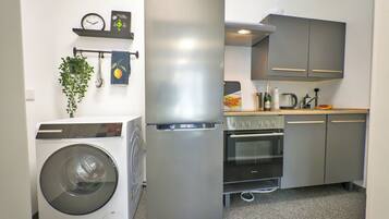 Eine kompakte Küche mit Waschmaschine, Kühlschrank, Backofen und Spüle.