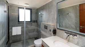Een moderne badkamer met een douche in een glazen cabine, een grote spiegel en een wit wastafelmeubel.