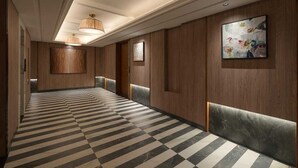 Un pasillo de hotel con suelo a cuadros, paneles de madera y una obra de arte enmarcada.