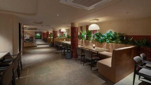 Een hotel lobby met een centrale trap, zithoeken en potplanten.