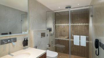 A modern bathroom with a glass-enclosed shower, a white sink, and a toilet.