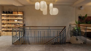 Un interior moderno con una escalera, lámparas colgantes y estanterías con cestas y frascos.