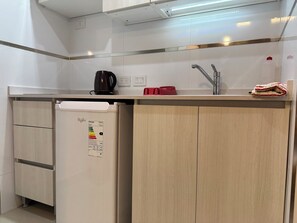 Eine kompakte Küchenzeile mit eingebautem Geschirrspüler, Kaffeemaschine und Spüle mit Armatur.