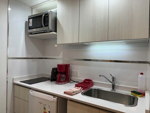 Eine moderne Küche mit Mikrowelle, Kaffeemaschine, Spüle und Geschirrspüler.