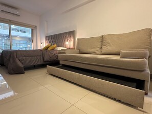 Ein modernes Schlafzimmer mit einem Bett, einer Couch und einer integrierten Ablage.