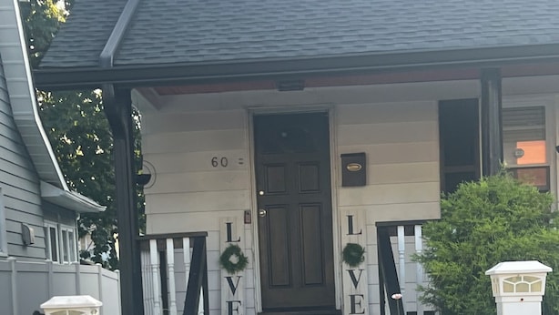 Ett hus med en veranda, ett vitt staket och en dörr där ordet ”KÄRLEK” är stavat med bokstäver på trappstegen.