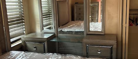 Un dormitorio con una cama grande, un aparador con cajones, un espejo y un armario.