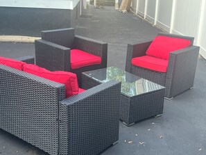 Outdoor wicker furniture with red cushions and a glass-top table.
