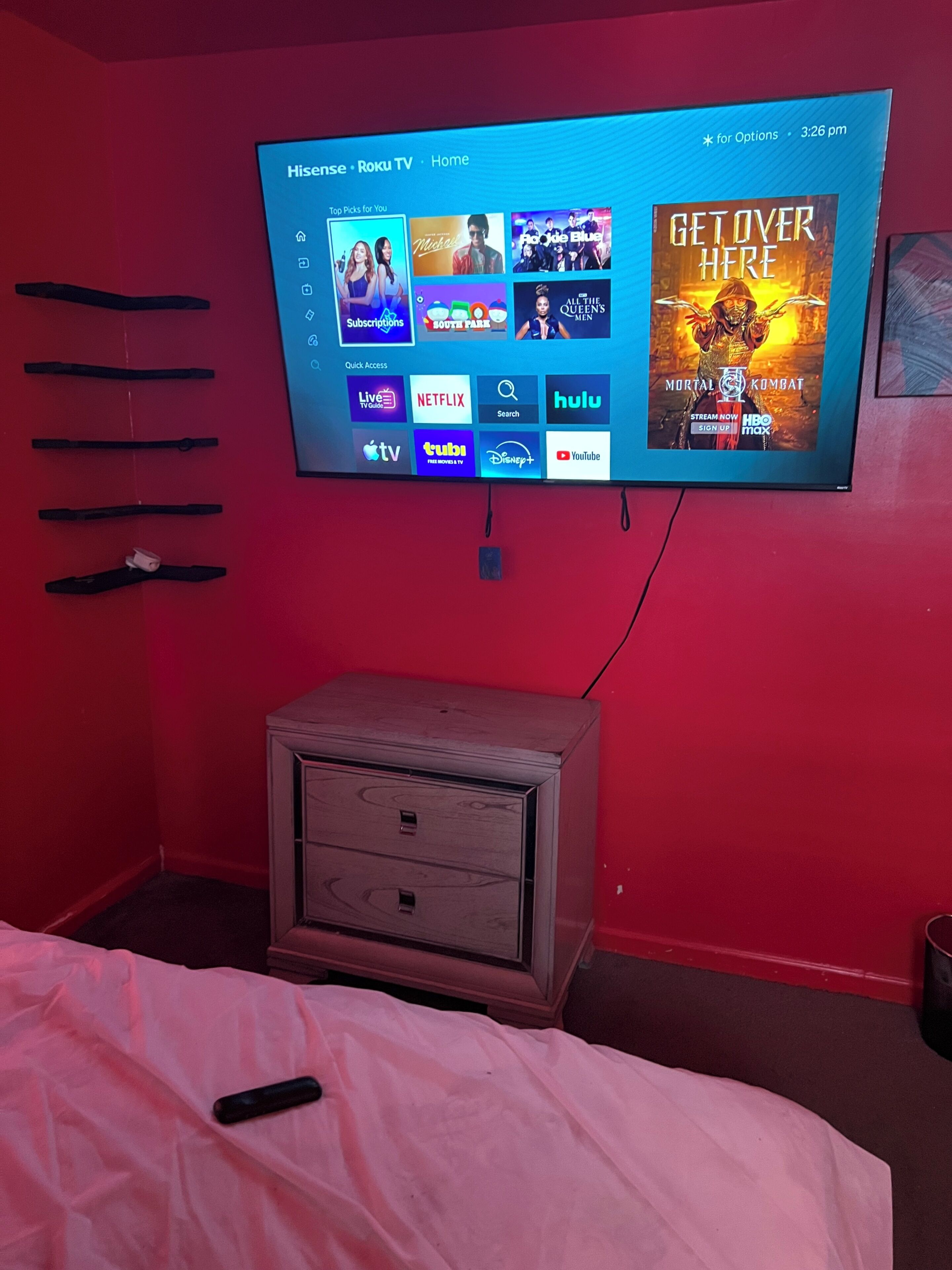 A television mounted on a red wall displaying a streaming service interface with various content options.