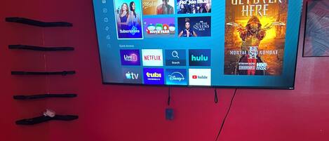 A television mounted on a red wall displaying a streaming service interface with various content options.