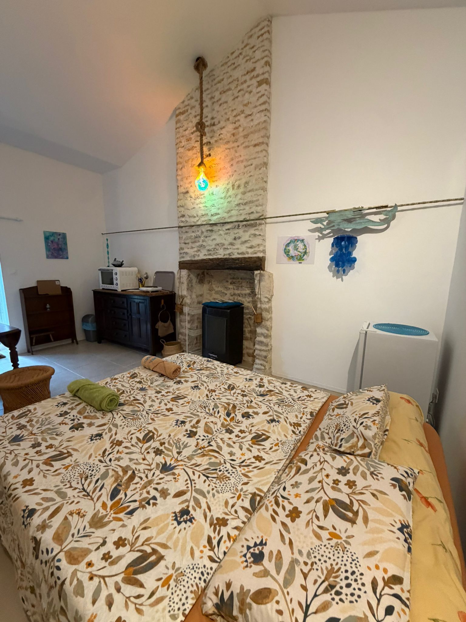 Une chambre à coucher comprenant un lit, une cheminée, un téléviseur et un luminaire fixé au mur.